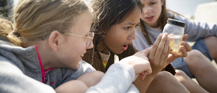 Three girls examine a glass of water